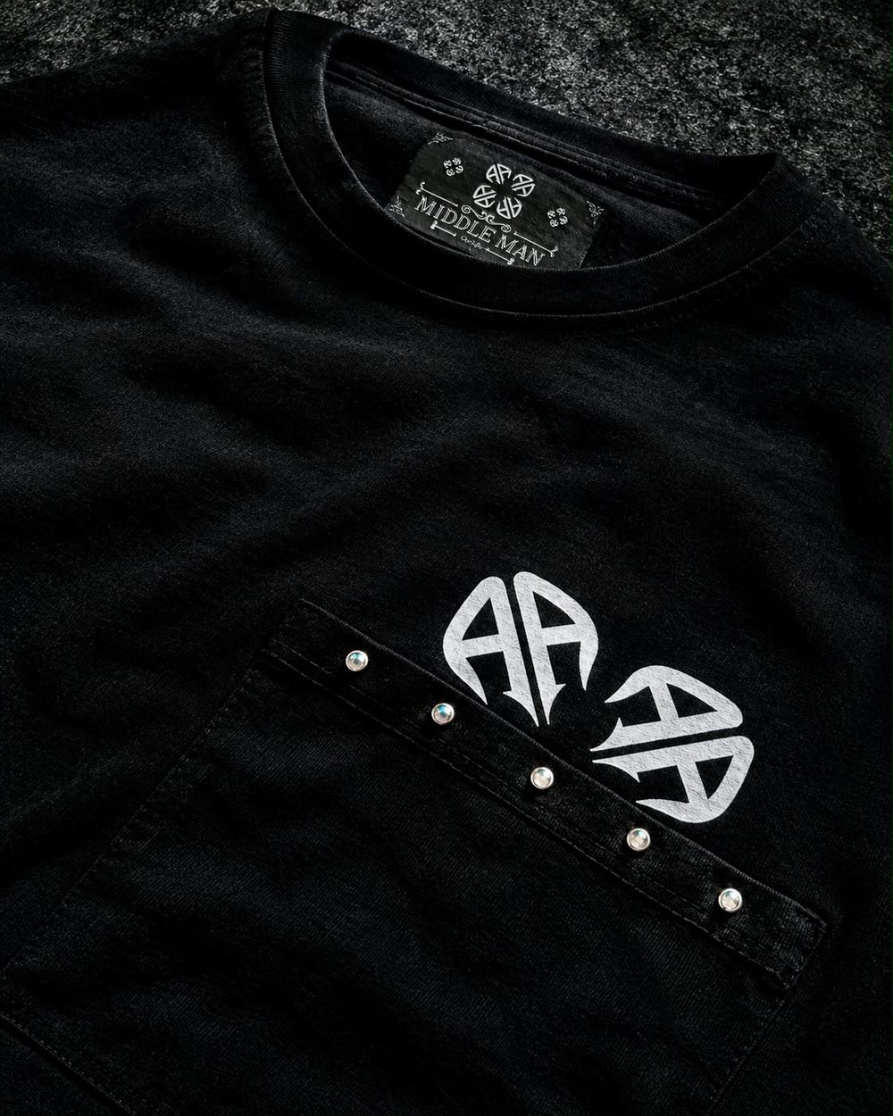 Detalle del cuello con la etiqueta y del bolsillo con tachuelas y logotipo